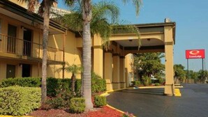 A hotel entrance with a covered walkway, palm trees, and a red sign for the Econolodge.
