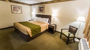 A hotel room with a bed, bedside tables, a chair, and a radiator.