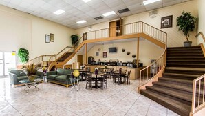 A spacious lobby with a central seating area, a staircase, and a reception desk.