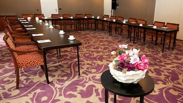 Ein Konferenzraum mit einem langen Tisch, Stühlen, einer floralen Tischdekoration und einem Teppichboden.