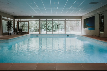 Una piscina techada, sillones reclinables de piscina