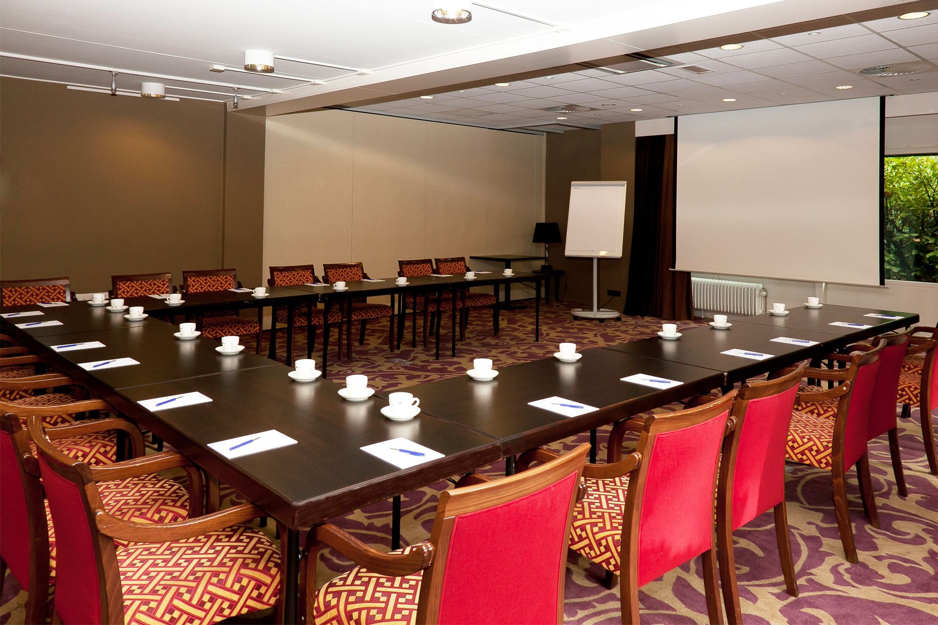 Une salle de conférence équipée d’une longue table, de nombreuses chaises et d’un écran de projection.