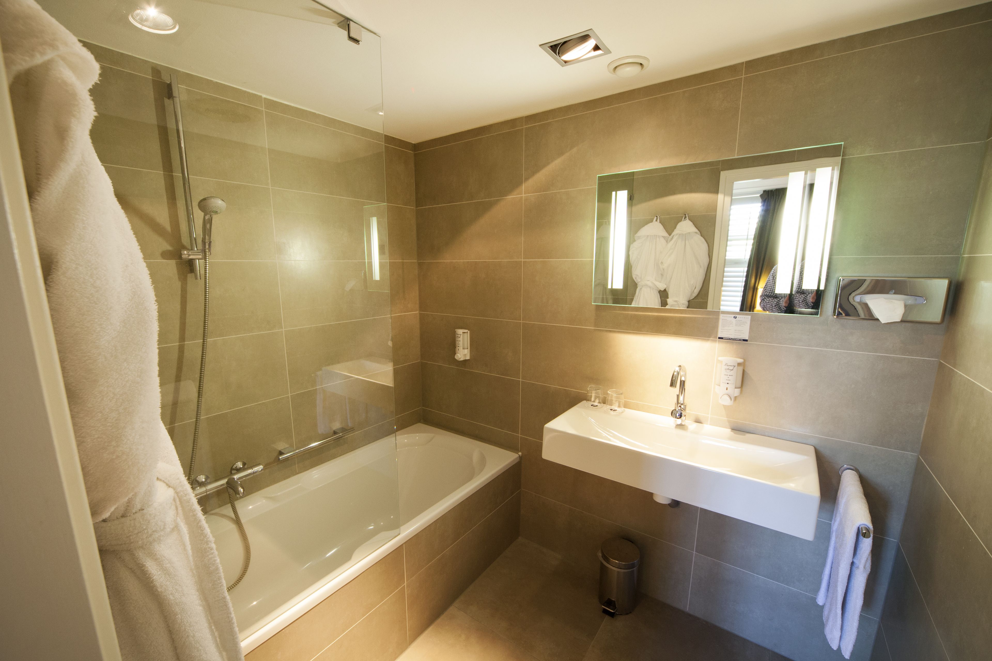 A modern bathroom with a glass-enclosed shower, a standalone bathtub, and a wall-mounted sink.