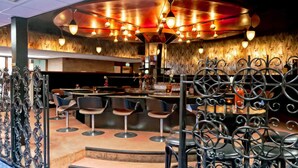 Una zona de bar con disposición circular de asientos, una barra y un techo decorativo con luces colgantes.