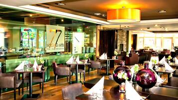 A restaurant with a bar area, multiple tables, and chairs.