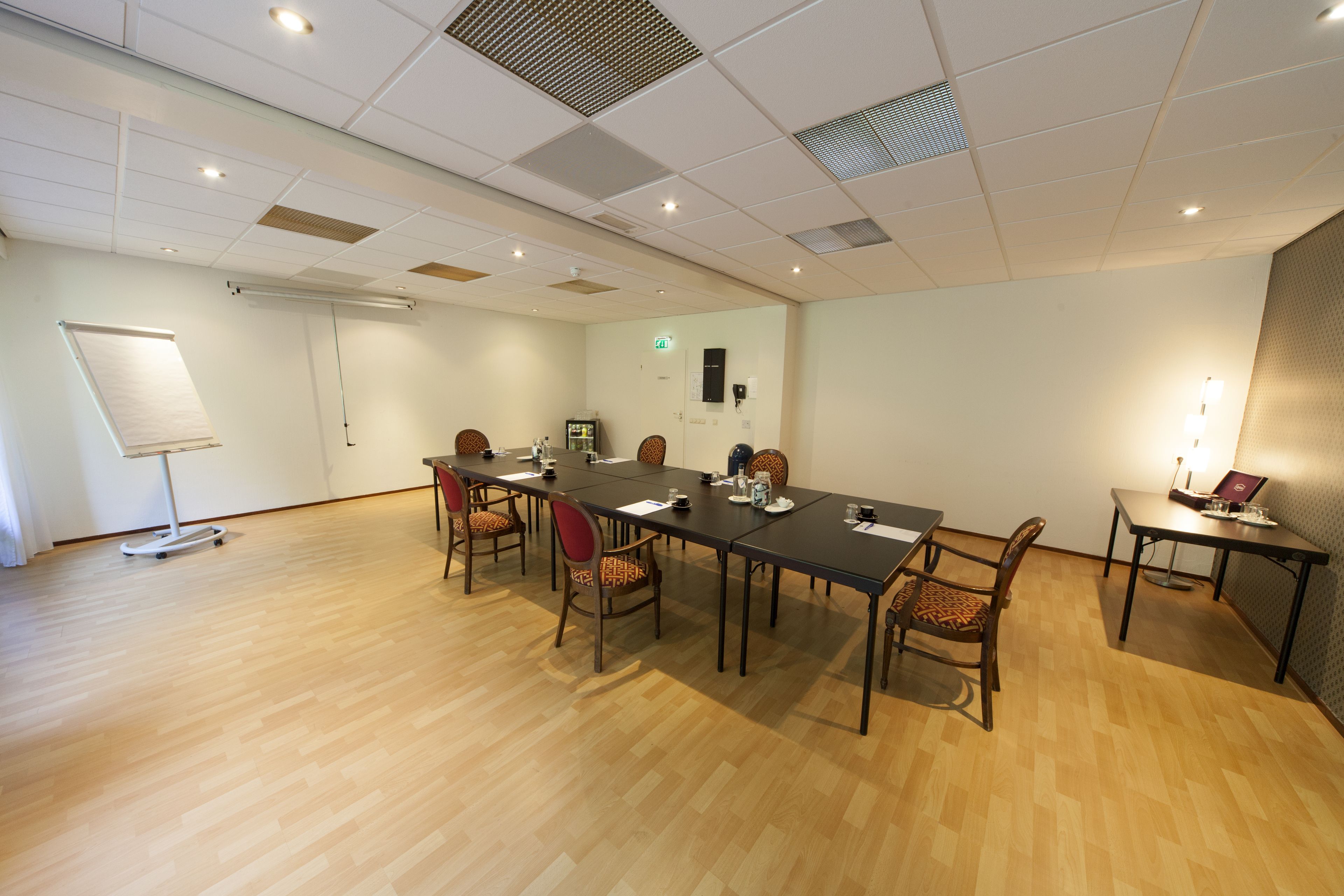 A conference room with a long table, several chairs, a whiteboard, and a projector.