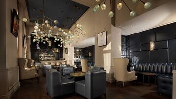 A modern lounge area with leather seating, a bar, and a chandelier.