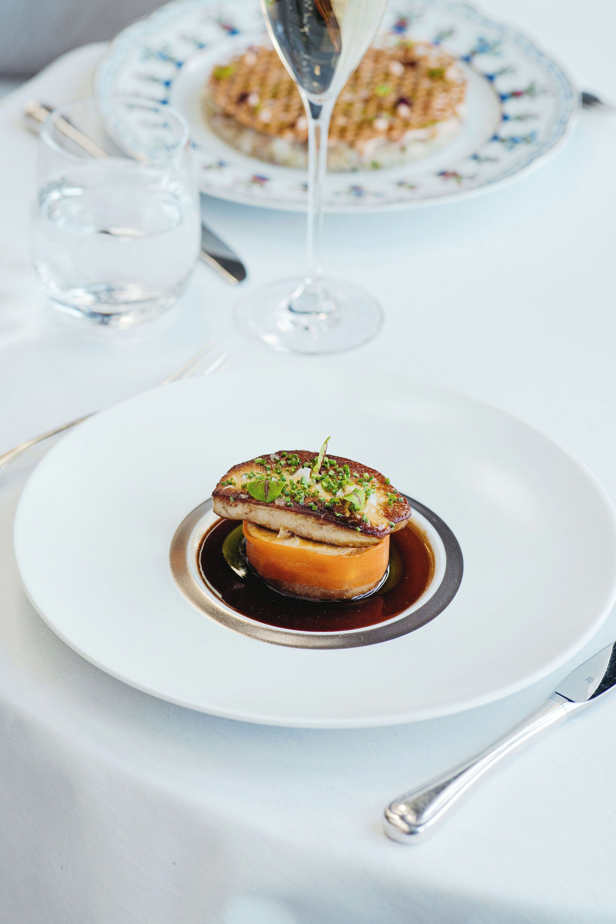 A dessert on a white plate with a glass of wine in the background.