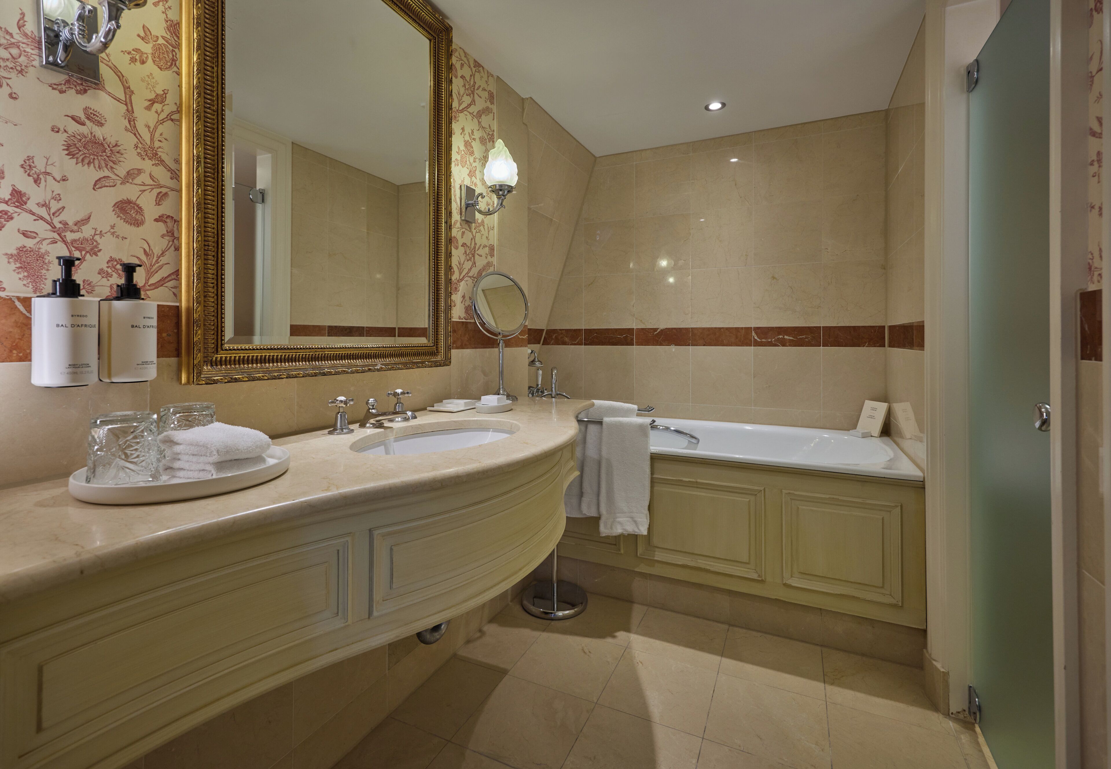A bathroom with two sinks, a large mirror, a bathtub, and a toilet.