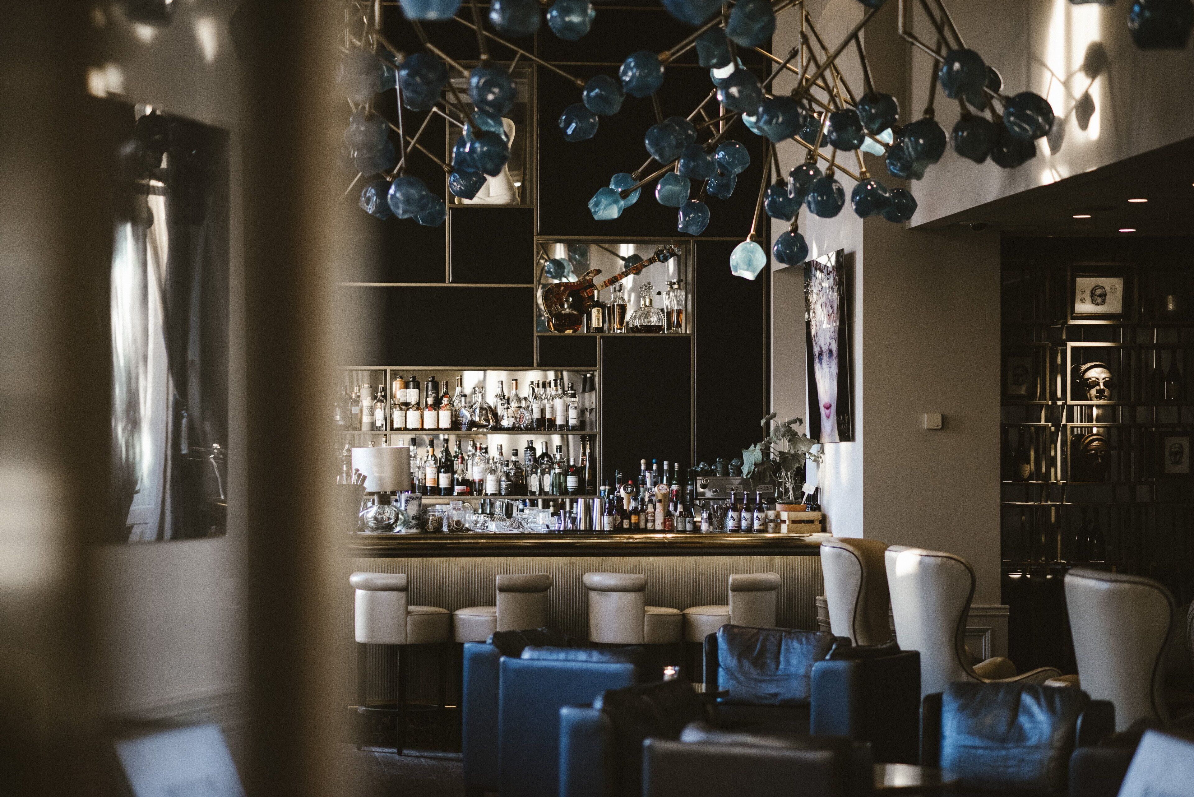 A bar area with seating, a well-stocked bar, and decorative hanging elements.