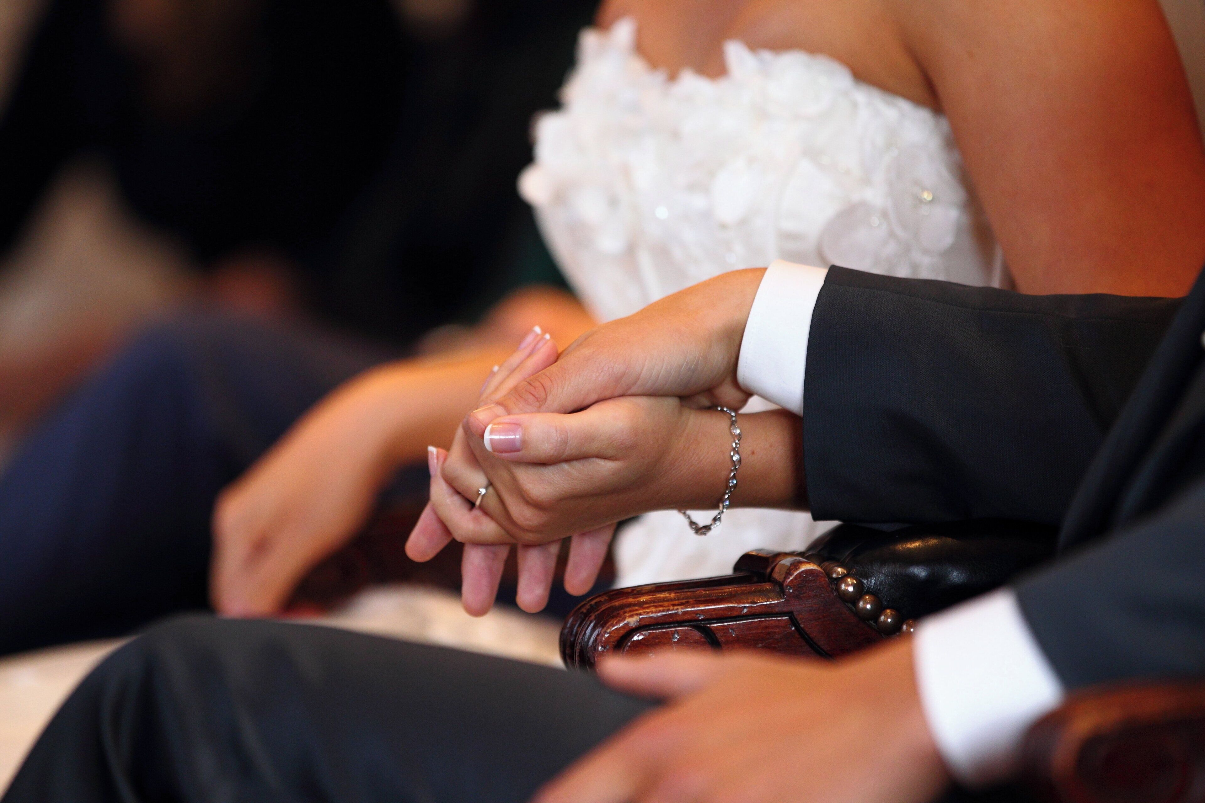 Close-up de uma aliança de casamento e uma pulseira de casamento na mão de uma pessoa.