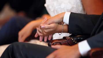 Close-up de uma aliança de casamento e uma pulseira de casamento na mão de uma pessoa.