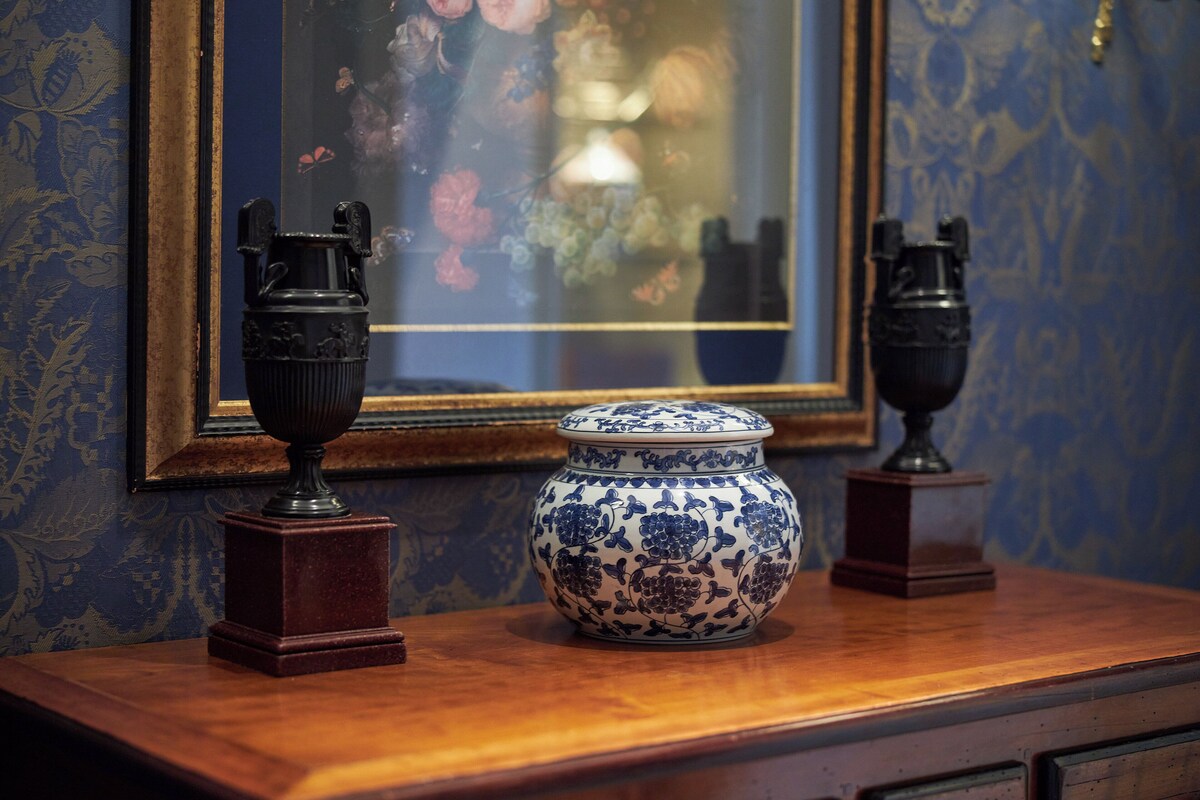 A wooden table with two decorative vases and a framed floral painting in the background.