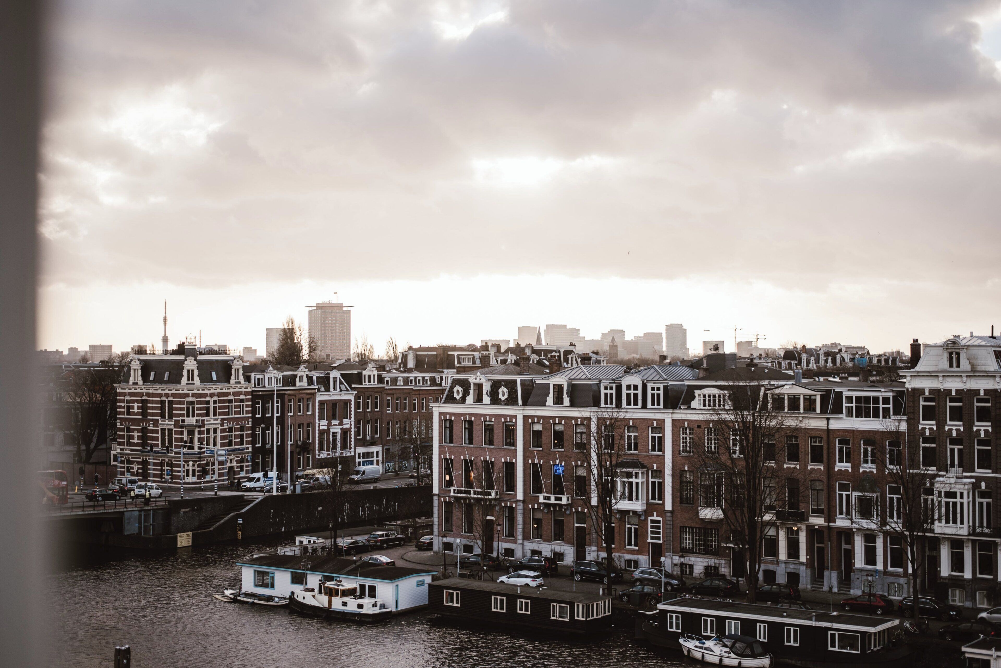 A canal-side view of a city with historic buildings and a boat docked at the water's edge.