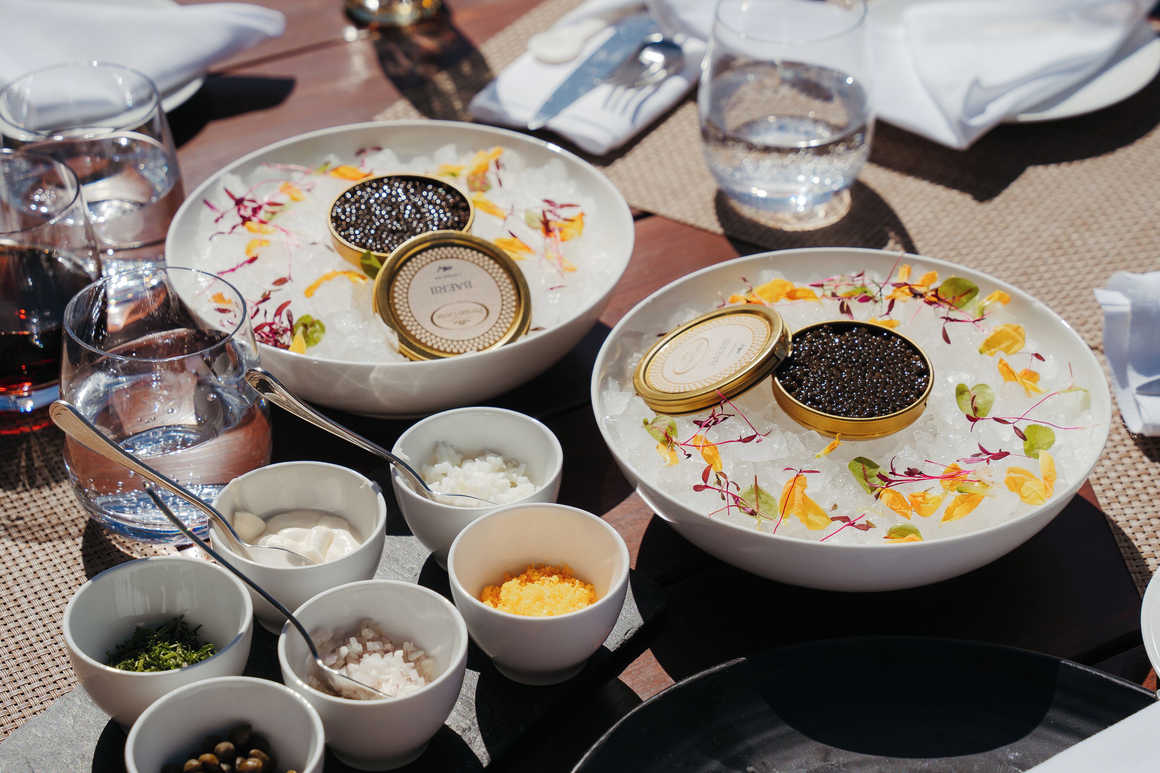 A table set with various dishes, including bowls with ice and garnishes, and glasses of water.