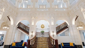 Eine prachtvolle Lobby mit einer zentralen Treppe, aufwendigen Kronleuchtern und einer großen, dekorativen Decke.