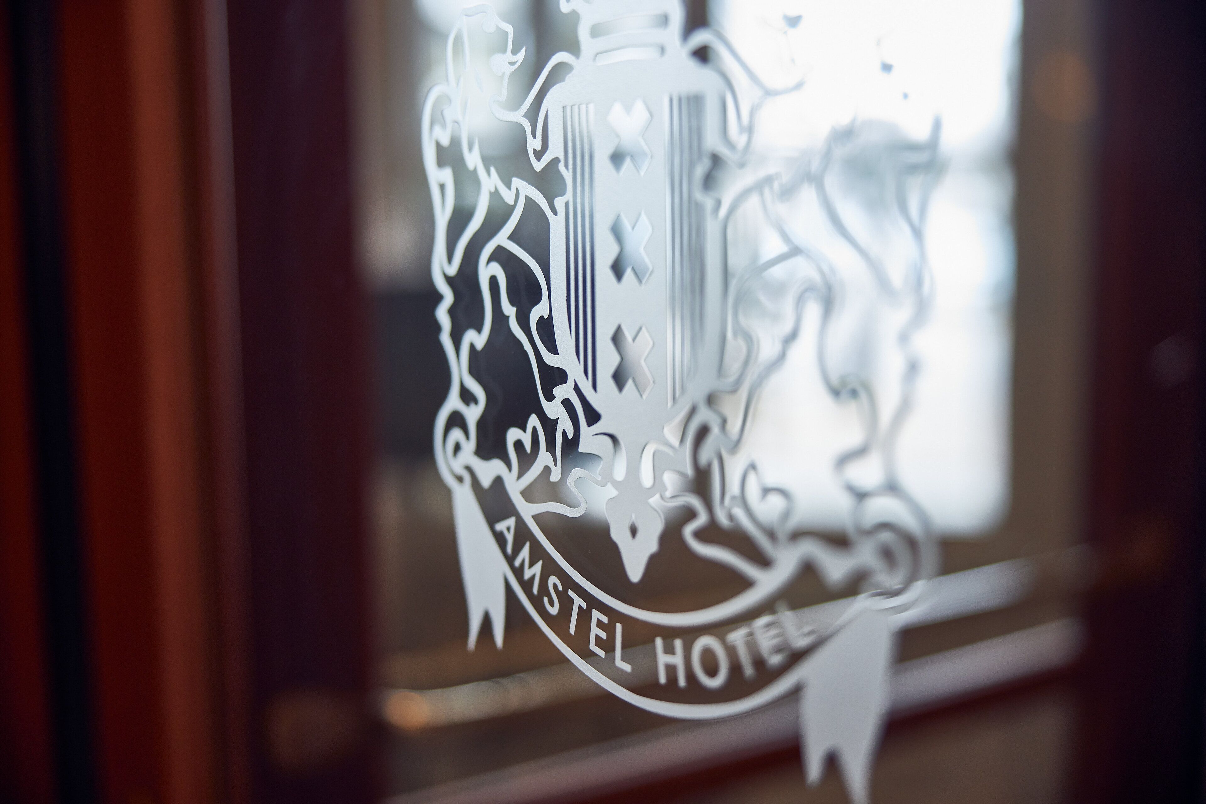 Un logo comprenant des armoiries et le texte « AMSTEL HOTEL ».