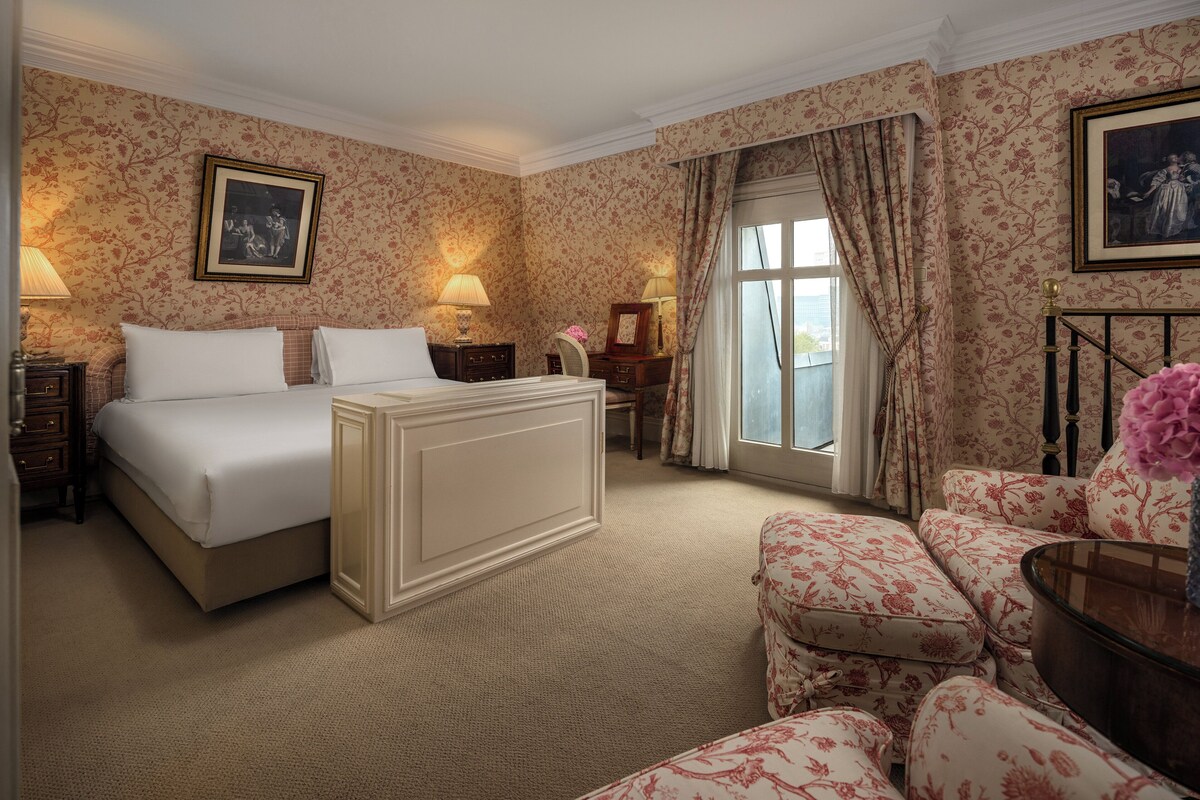 Ett hotellrum med en stor säng, en soffa, ett skrivbord och ett fönster med gardiner.