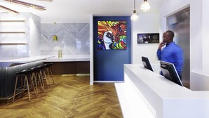 A modern reception area with a marble wall, a colorful abstract painting, and a bar with stools. - VISIONAPARTMENTS Geneva Gare  (Geneva)