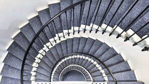 A spiral staircase with a black metal railing and white steps. - VISIONAPARTMENTS Geneva Gare  (Geneva)