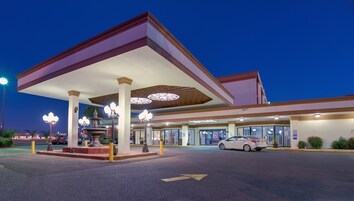 Posto de gasolina com toldo, várias bombas de combustível e um carro estacionado na frente.