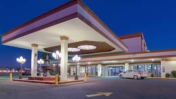 A gas station with a canopy, a fountain, and a car parked in front.