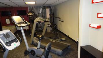 Uma academia com equipamentos de cardio, esteira e bicicleta ergométrica.