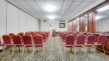 Ein Konferenzraum mit Reihen von Stühlen, einem langen Tisch und einem gemusterten Teppich.