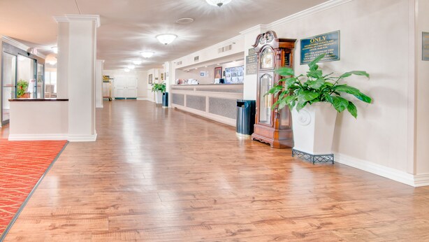 A spacious hallway with wooden flooring, a reception desk, and a clock on the wall.