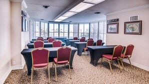 A conference room with tables and chairs, large windows, patterned carpet, and framed pictures on the walls. - Clarion Hotel & Suites (Metairie)