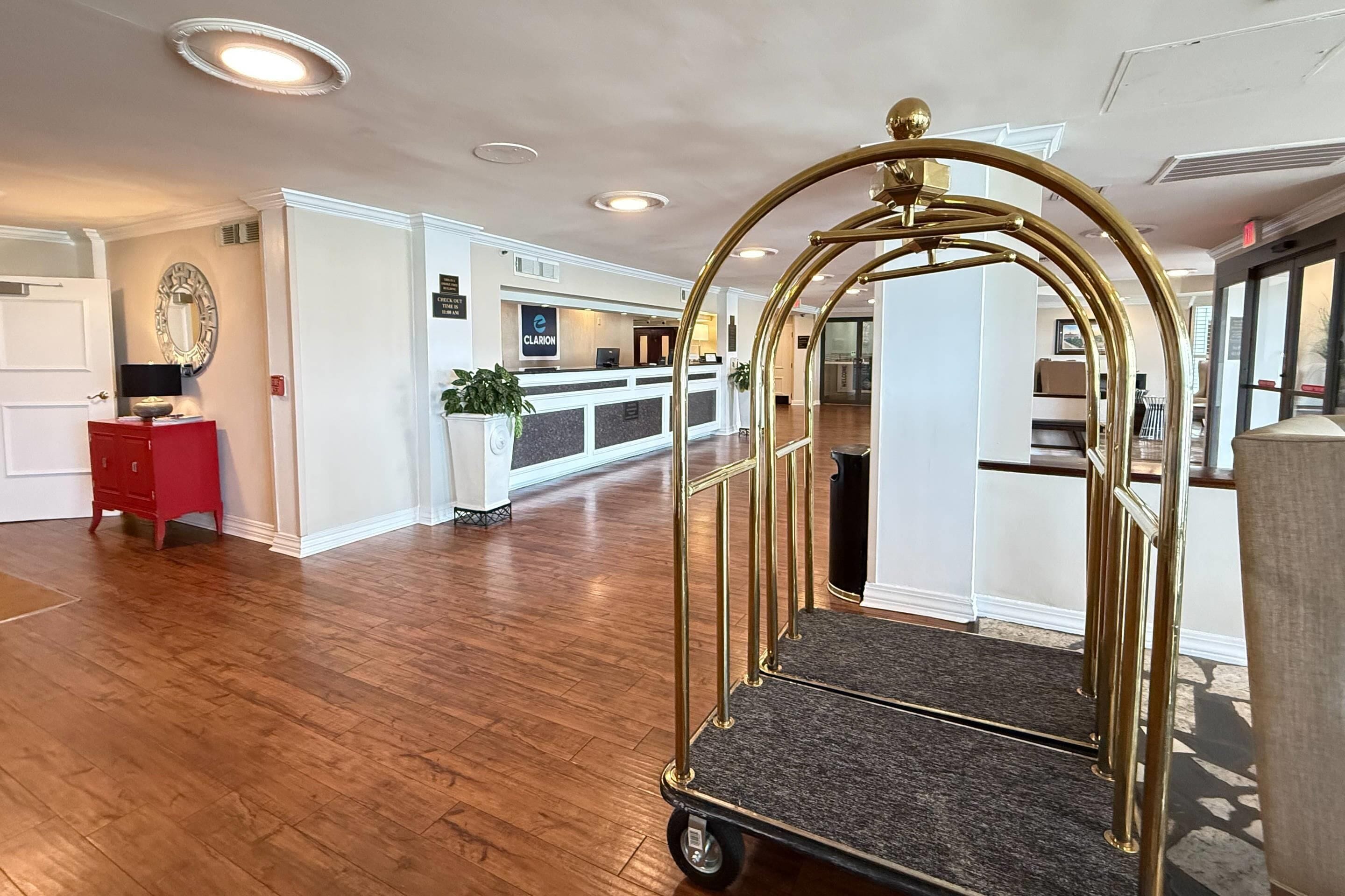 A hotel lobby with a reception desk, a red cabinet, and a gold-framed cart.