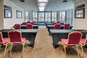 A conference room with a long table, red chairs, and patterned carpet. - Clarion Hotel & Suites New Orleans Airport (Metairie)