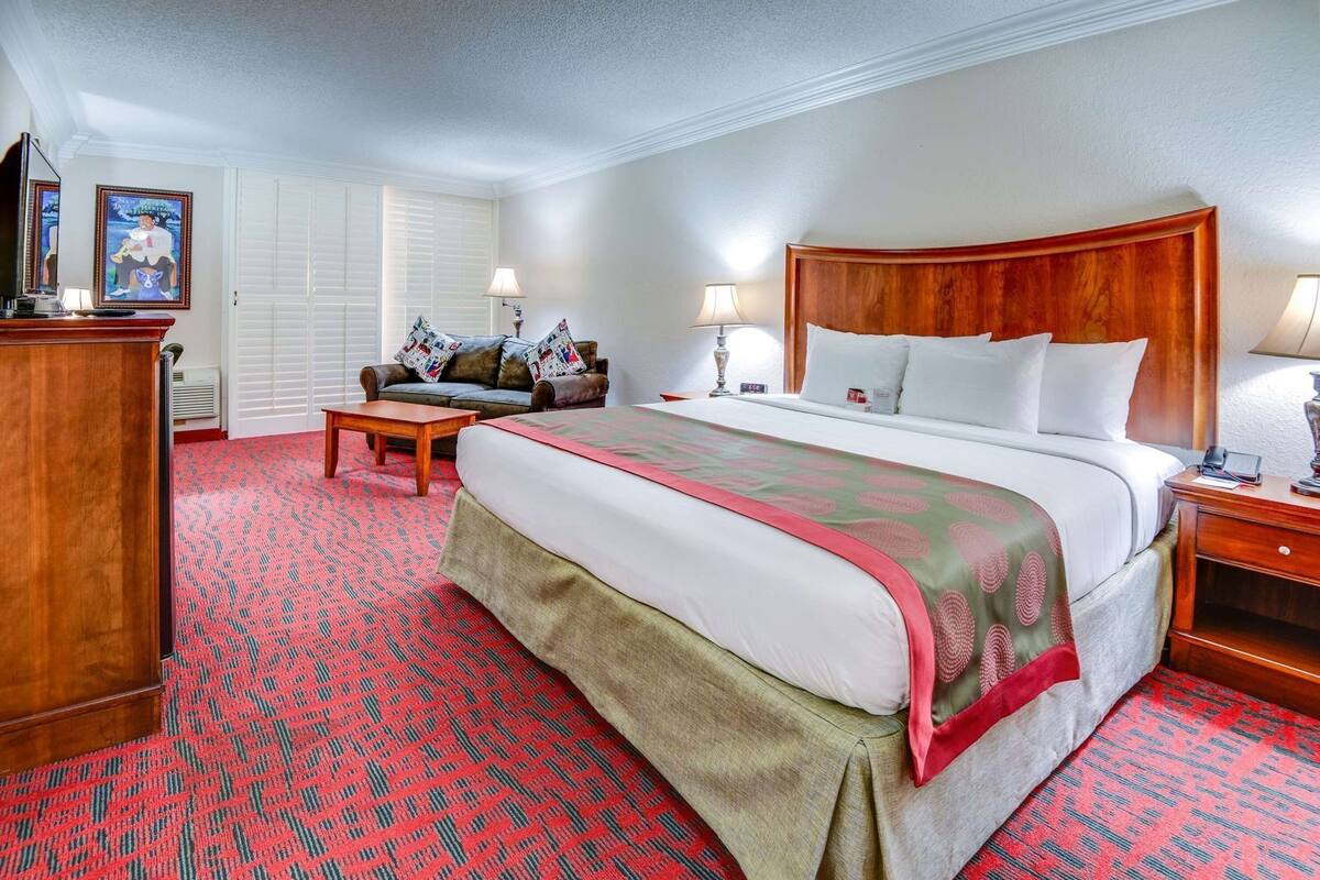 Ein Hotelzimmer mit einem großen Bett, einem Holzkopfteil, einem Schreibtisch, einem Stuhl und einer Couch.