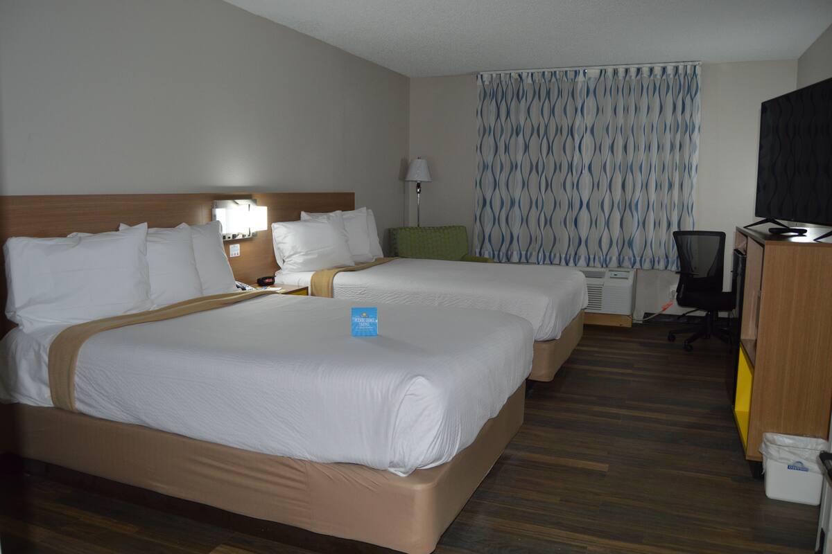 Une chambre d’hôtel avec deux lits, un bureau, une chaise et un téléviseur.