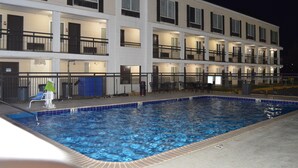 Un hôtel doté d’une piscine, de plusieurs balcons et d’une façade bien éclairée.