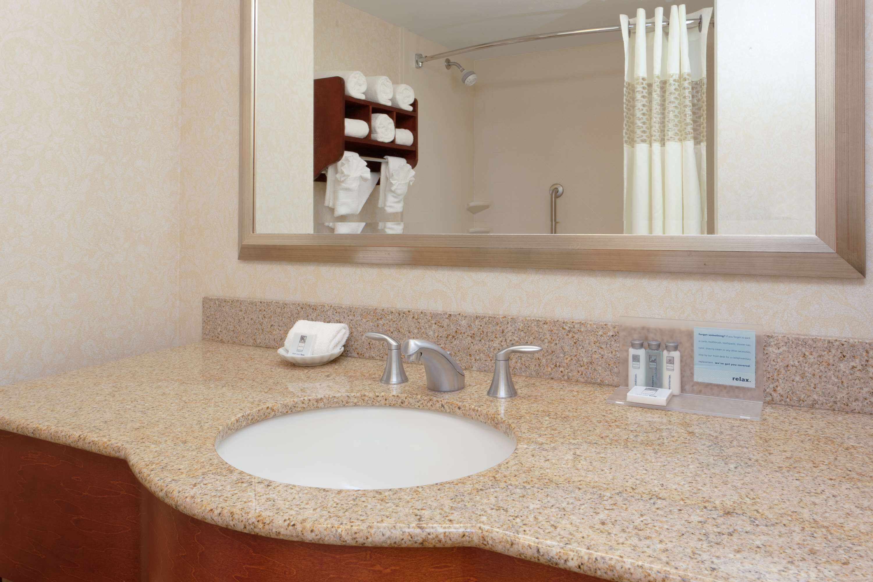 A bathroom with a granite countertop, a white sink, and a mirror above it.