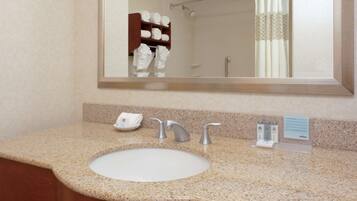 A bathroom with a granite countertop, a white sink, and a mirror above it.
