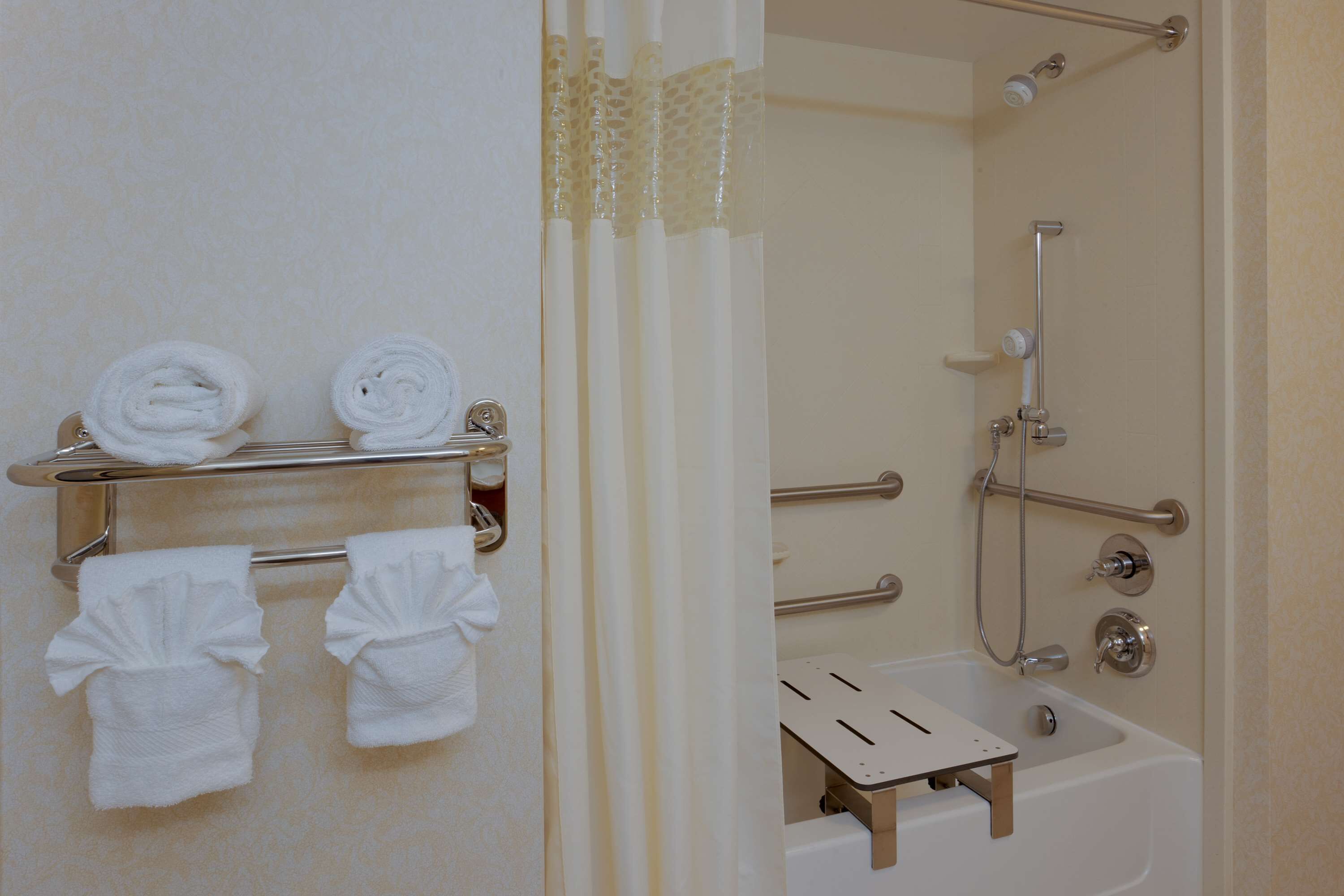 A bathroom with a shower, a bathtub, and a towel rack with towels.