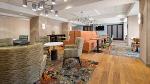 Un amplio vestíbulo de hotel con varias zonas de estar, un sofá central y un comedor.