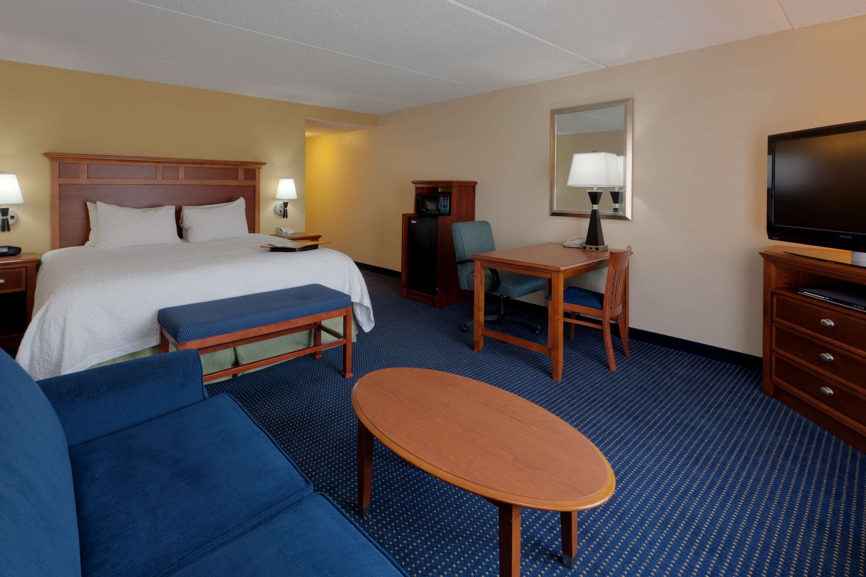 Una habitación de hotel con cama, escritorio, televisor y sofá.