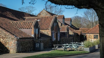 A stone building with a traditional roof, a picnic table, and a sign indicating a pet-friendly area.