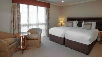 A hotel room with two beds, a round table, and a sofa.