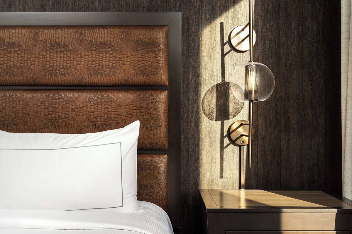 A neatly made bed with white linens and a headboard with a textured pattern.