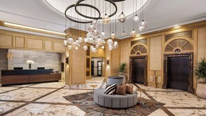 A spacious lobby with a marble floor, a reception desk, a seating area with a round ottoman, and a large chandelier. - DoubleTree Suites by Hilton Austin Downtown Capitol (Austin)