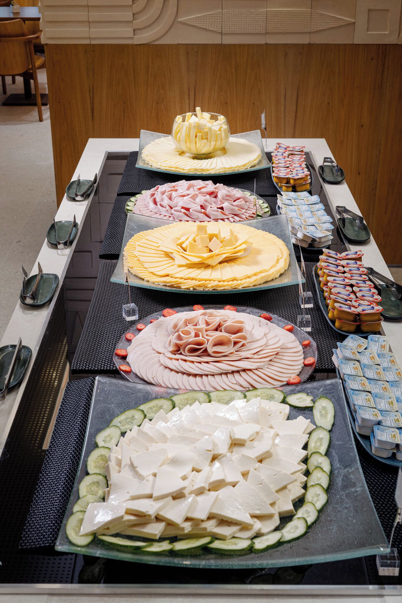 En buffetbord med forskellige spiser, herunder ost, kød og grøntsager.