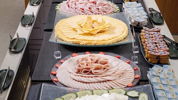 En buffetbord med forskellige spiser, herunder ost, kød og grøntsager.