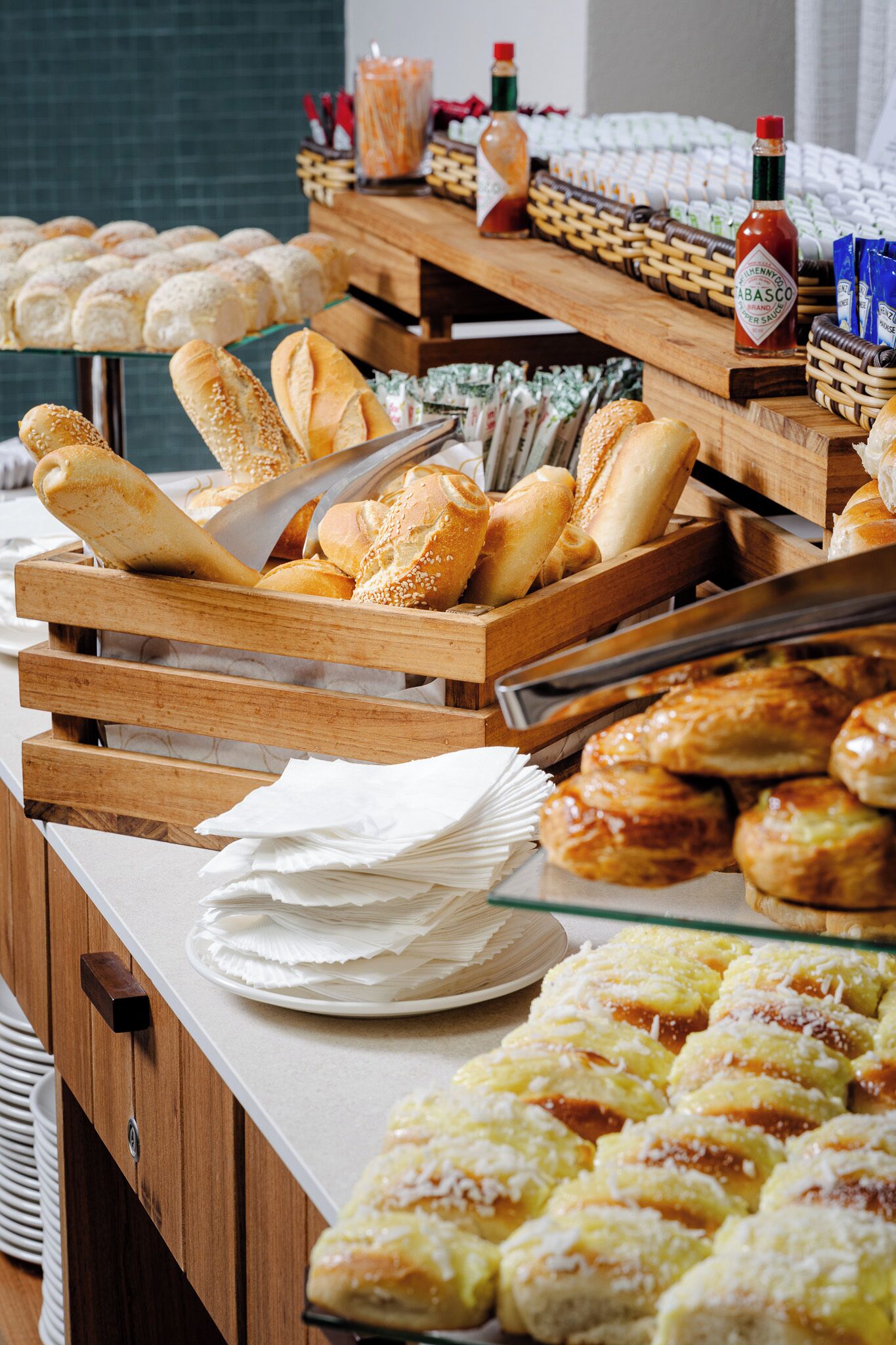 A buffet with various breads and pastries, including baguettes and croissants, arranged on wooden stands.