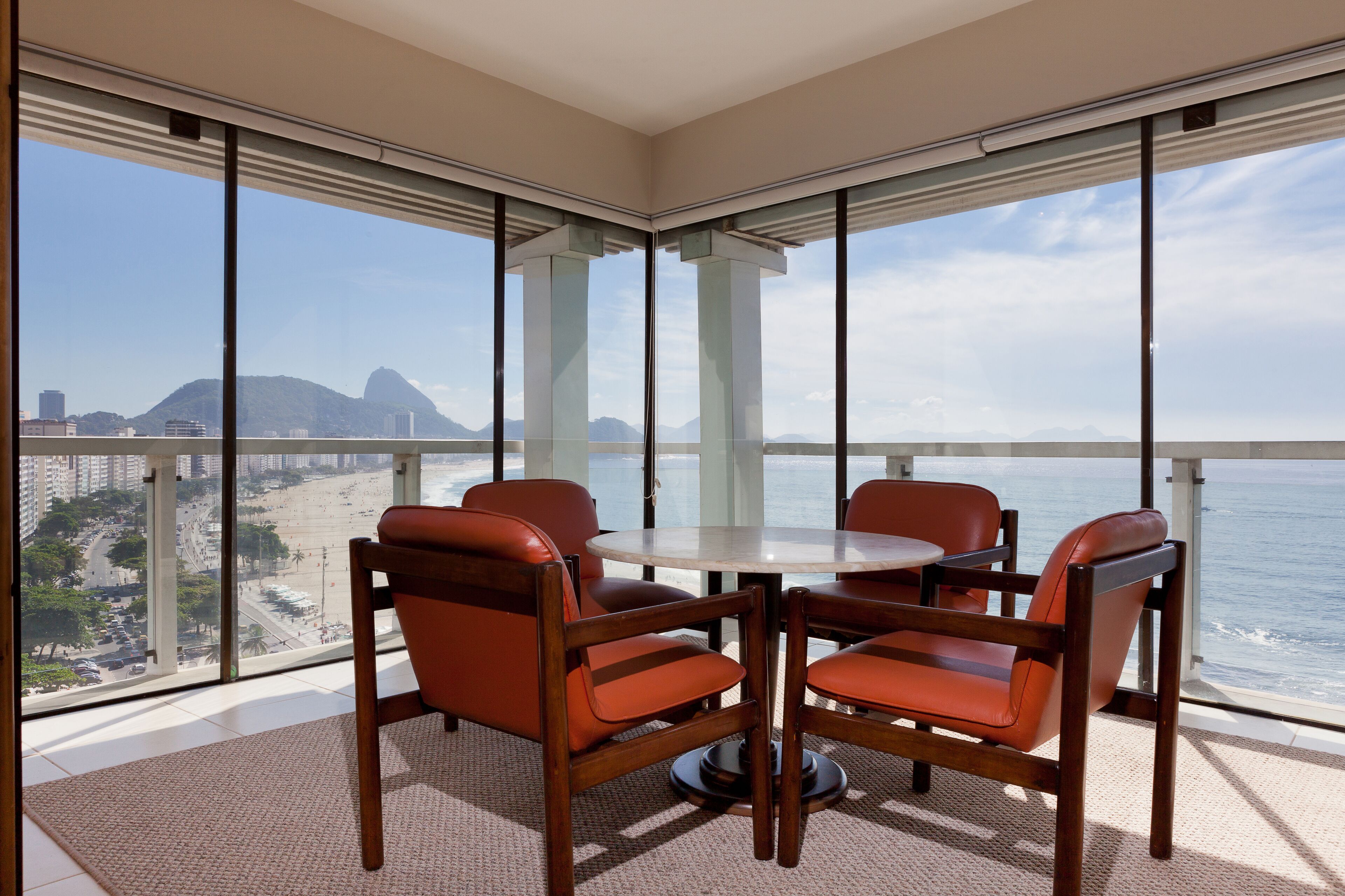 Un balcon avec une table et des chaises, offrant une vue sur la plage et le paysage urbain.