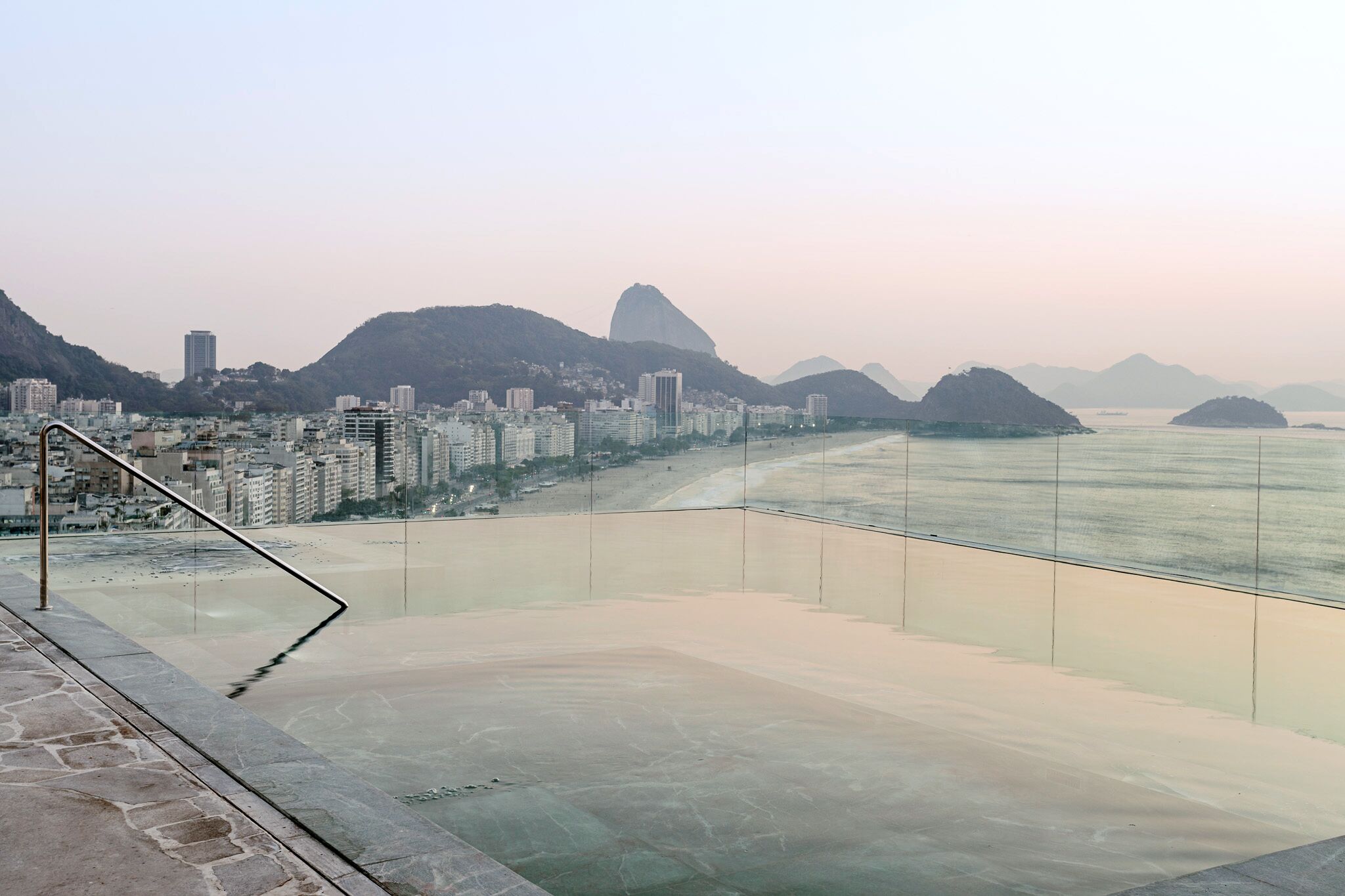 A coastal cityscape with a prominent mountain and a beach.