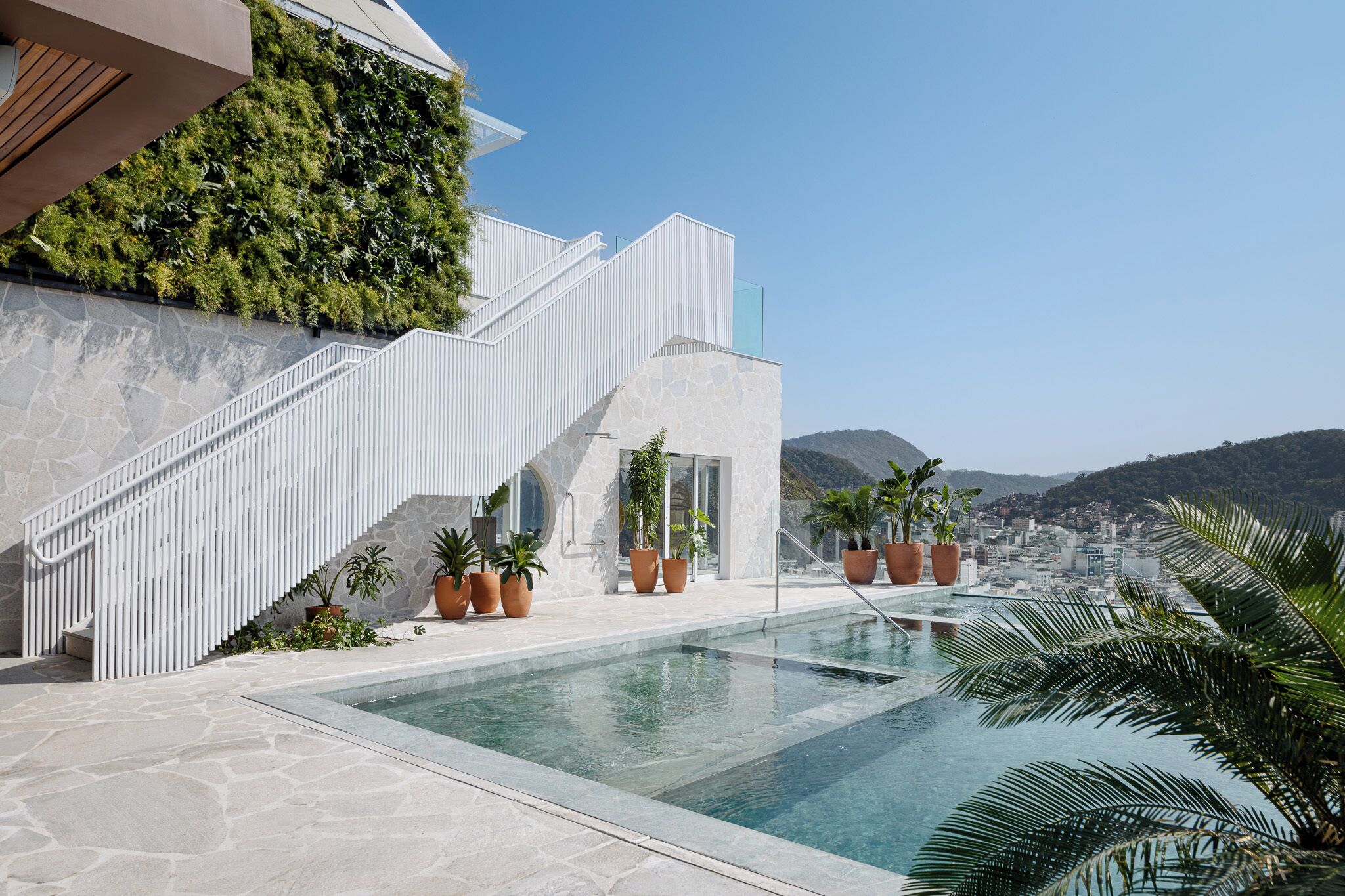 Un edificio moderno con piscina, escaleras y plantas en macetas.